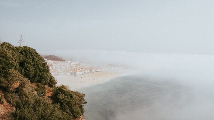 Mglista plaża i wybrzeże Nazaré w Portugalii z lotu ptaka Mglista plaża i wybrzeże Nazaré w Portugalii z lotu ptaka
