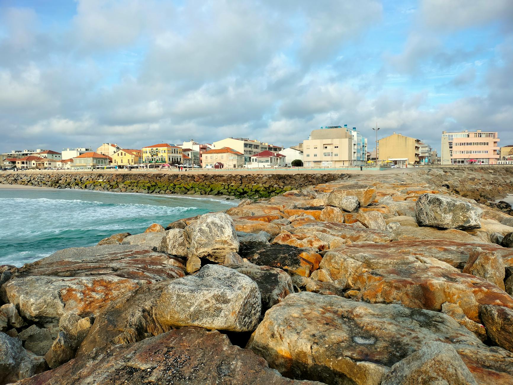 Skalista plaża i nadmorskie miasteczko w Portugalii pod pochmurnym niebem