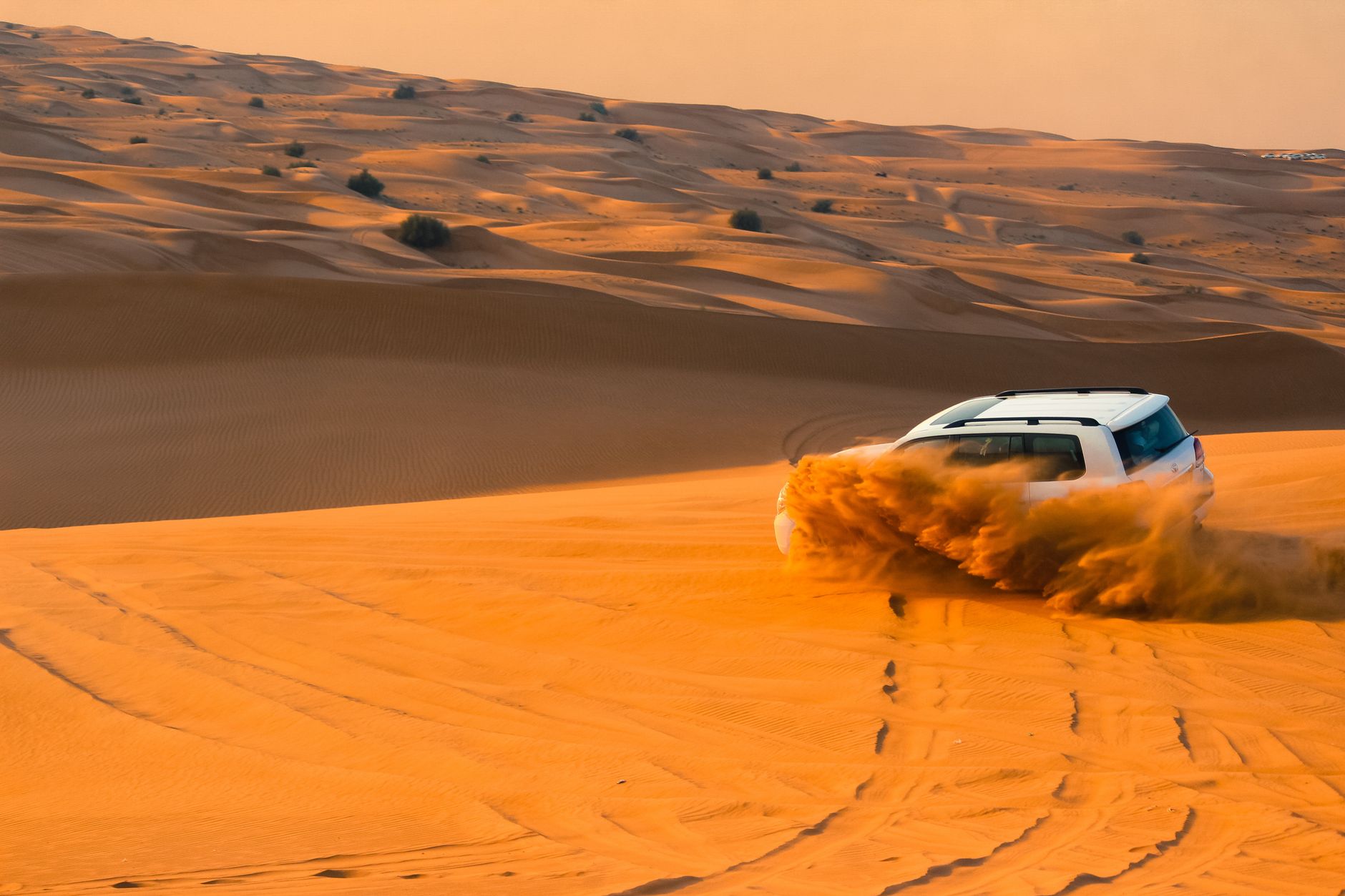 SUV na wydmach pustyni pod Dubajem o zachodzie słońca