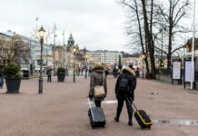 Turyści z walizkami spacerują po centrum Helsinek w pochmurny dzień