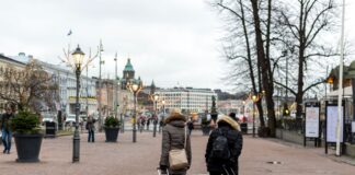 Turyści z walizkami spacerują po centrum Helsinek w pochmurny dzień