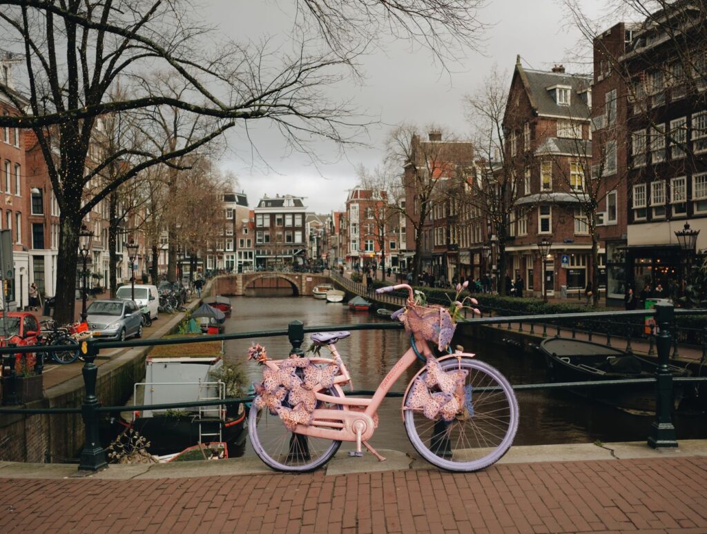 Kanał w Amsterdamie, zabytkowe kamienice i różowy rower