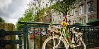 Rower ozdobiony kwiatami przy moście nad kanałem w Amsterdamie