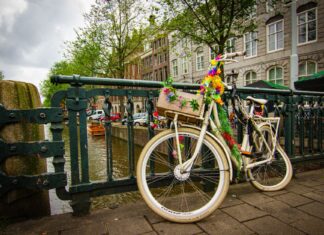 Rower ozdobiony kwiatami przy moście nad kanałem w Amsterdamie