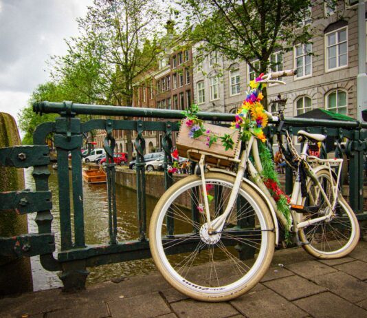 Rower ozdobiony kwiatami przy moście nad kanałem w Amsterdamie